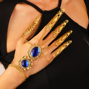 Detalle de joyería dorada para danza del vientre con piedras azules y fundas de uñas