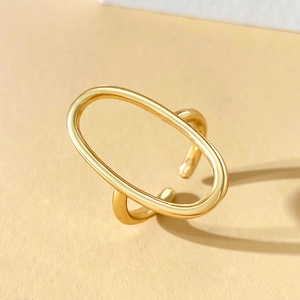 Macro detail of a golden geometric oval open ring with minimalist hollow-out design
