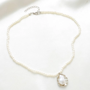Bohemian pearl necklace with baroque pearl shell pendant on white silk background