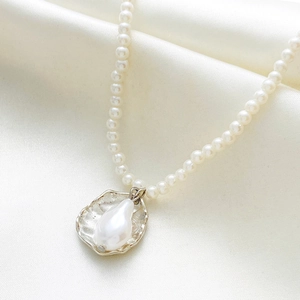Detailed macro of white Baroque pearl pendant and freshwater pearls on silk background
