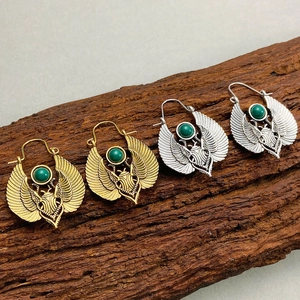 Vintage Egyptian scarab beetle earrings with green gemstone on wood display