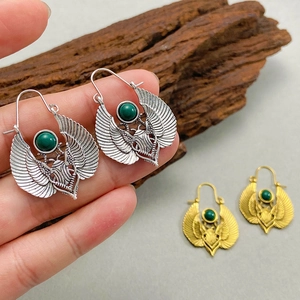 Detailed macro view of vintage Egyptian scarab earrings with green stone and wing carvings