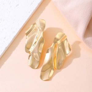 Detail of gold irregular wavy earrings with a high-polished metallic finish and fluid design