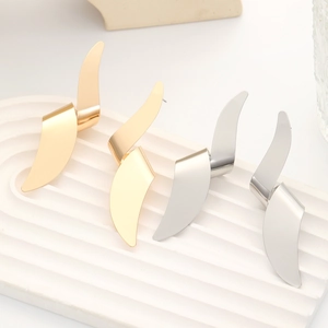 Macro view of gold and silver irregular metallic petal earrings on a white pedestal
