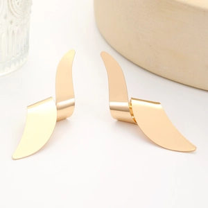 Detailed view of polished golden irregular twisted petal earrings on minimalist background