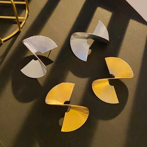 Macro detail of geometric twisted fan earrings showing gold and silver pleated textures