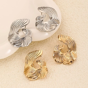 Detail showing large irregular spiral metal earrings in shiny gold and silver finishes