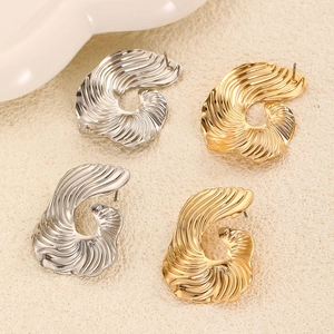 Detailed macro view showing gold and silver spiral metal earrings with textured finish