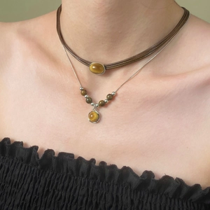 Close-up of double-layered necklace set with tiger eye pendants and brown wax cord