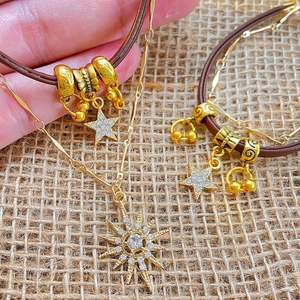 Macro detail of gold-plated starburst pendant and brown leather choker on burlap