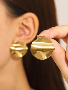 Macro view of gold irregular wave textured earrings with high polish metallic finish