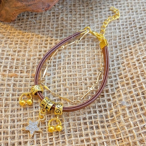 Detail of bohemian layered brown leather bracelet with gold star charm and beads