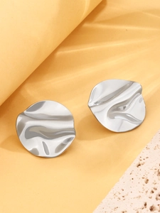 Detail of silver irregular metallic earrings with textured ripple surface and minimal design