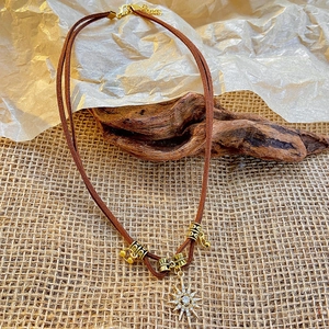Detailed view of bohemian double-layer brown leather necklace with starburst sun pendant