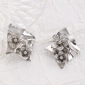Detail of silver irregular metal earrings featuring textured hammer-finish floral designs