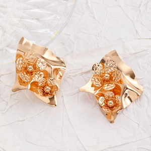 Macro detail of large gold flower earrings with irregular hammered metal and floral texture