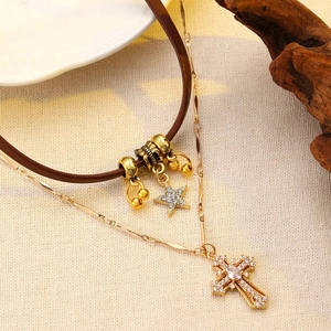 Detailed close-up of brown leather choker and gold cross pendant with clear gemstone