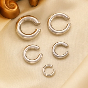 Dettaglio di cinque ear cuff argentati graduati su un pregiato sfondo di seta calda