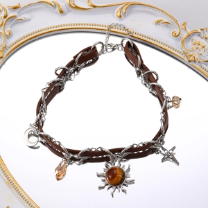 Detail of a brown leather choker featuring a sun star pendant and amber bead charms