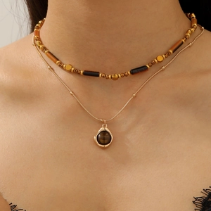 Detail of layered brown leather choker with golden beads and tiger eye sun pendant