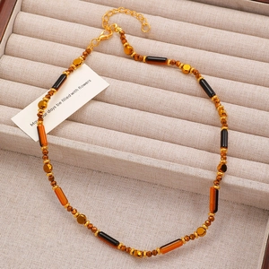 Close-up of handmade beaded choker with amber beads and gold lobster clasp detail