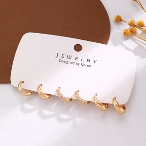Set di tre paia di orecchini a cerchio dorati geometrici con strass su scheda di supporto