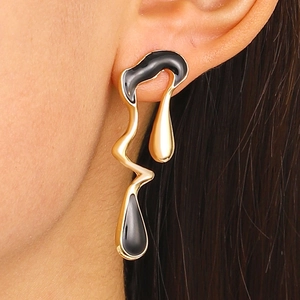 Detail of elegant gold metal earrings with liquid black resin on a model's ear