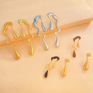 Detailed view of liquid metal style earrings with gold silver and enamel finish drip design