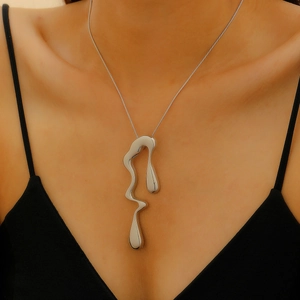 Close-up of irregular liquid-style silver geometric pendant on a minimalist chain necklace
