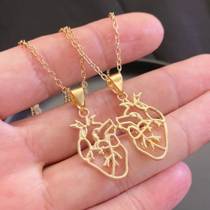 Detailed close-up of two golden anatomical heart necklaces for friends or couples
