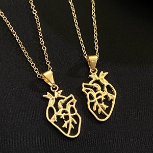 Macro shot of gold anatomical heart pendants with hollow vascular details on fine link chains