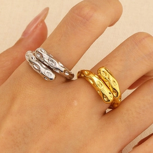 Detail of gold and silver textured open rings with liquid metal finish on a hand