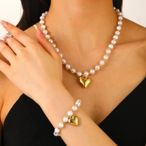 Detail of elegant gold heart pendant and white pearl necklace set on model