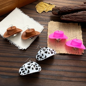 Cowboy hat disco ball drop earrings in brown, pink, and cow print on wood background
