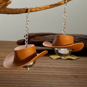 Detail of disco ball earrings with brown cowboy hats hanging on a wooden branch
