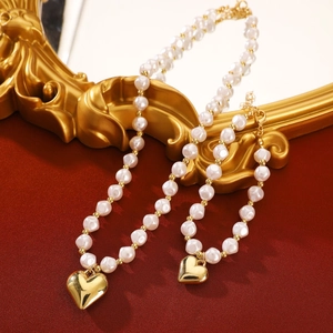 Detail of pearl jewelry set with golden heart pendant on vintage red fabric background