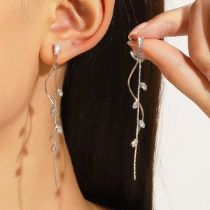 Macro view of gold tassel earrings with leaf patterns and sparkling zircon stones