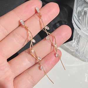 Detail of elegant gold tassel earrings with marquise-cut zircons and twisted chains