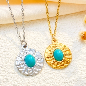 Detail of vintage turquoise pendants with hammered texture in gold and silver finish
