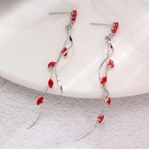 Detail of silver drop earrings with red marquise gems placed on a white porcelain dish