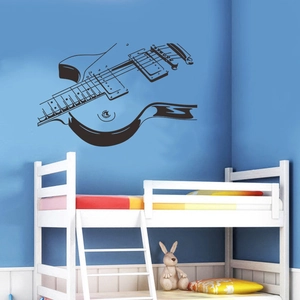 Gros plan du sticker mural guitare électrique noire affiché sur un lit dans une chambre moderne