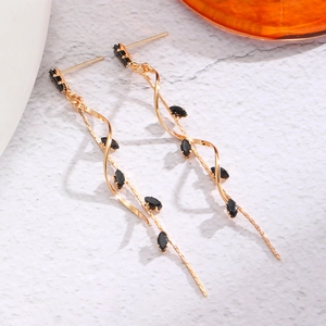 Detail shot of elegant gold flower tassel earrings with black marquise gemstones on marble