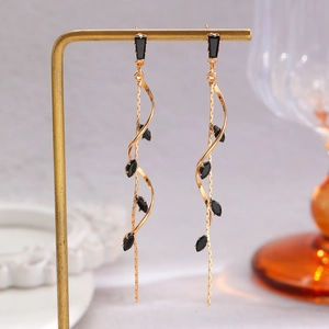 Detail of luxury gold tassel earrings with black crystals on a display stand