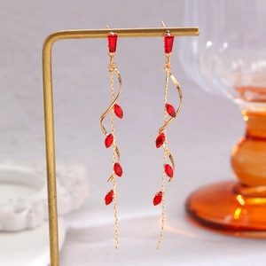 Macro detail of elegant gold leaf tassel earrings featuring marquise red gemstones