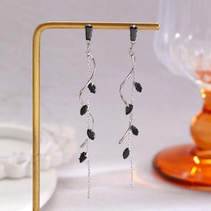 Detailed close-up of long tassel earrings with black marquise-cut stones on a gold stand