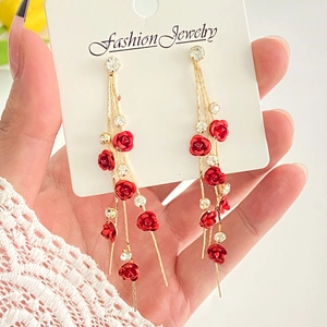 Detailed macro view of red rose earrings with sparkling rhinestone tassels and gold chain