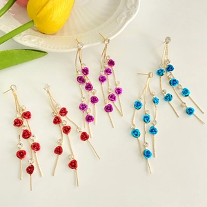 Detail of elegant long tassel earrings with rose charms and crystals in red, blue and purple