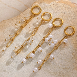 Detail of long gold tassel earrings with crystal beads and white faux pearls on stone