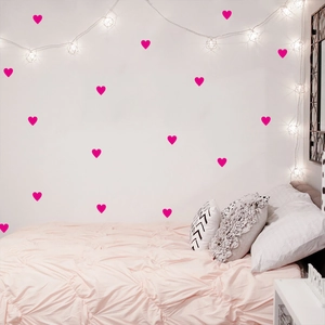 Rose red heart wall stickers displayed over a cozy white bedroom wall with fairy lights