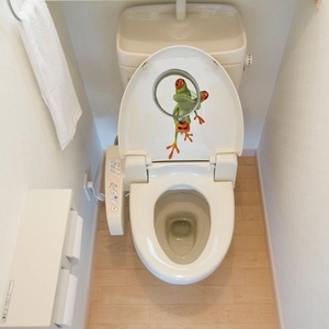3D realistic green frog holding a magnifying glass sticker applied to a white toilet lid